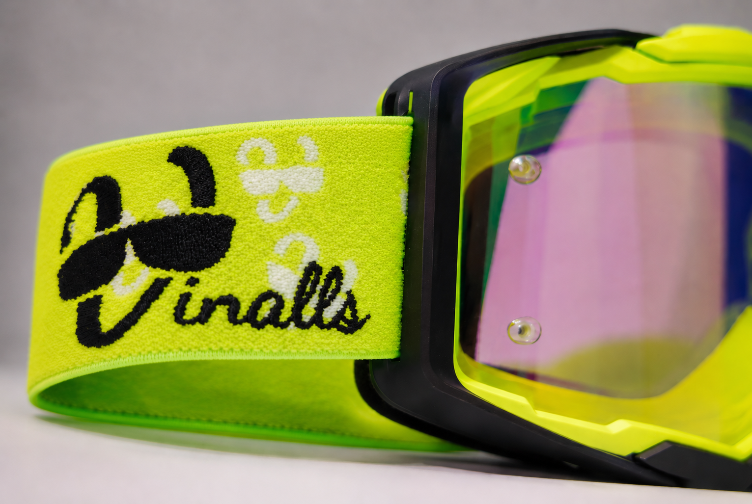 Close-up of a pair of goggles with a bright green strap featuring 'Vinalls' branding.
